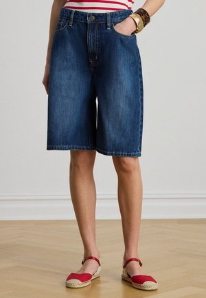 Denim Bermuda-shorts i mørk blå med en avslappet passform, fem lommer og synlige sømdetaljer. Kombinert med røde espadrillos.