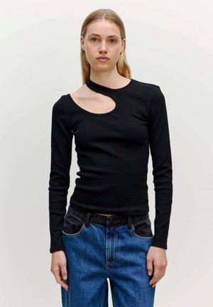 Zwarte langekmouwen top met een unieke asymmetrische uitsnijding bij de hals, gemaakt van ribbelstof. G gedragen met blauwe high-waisted jeans.