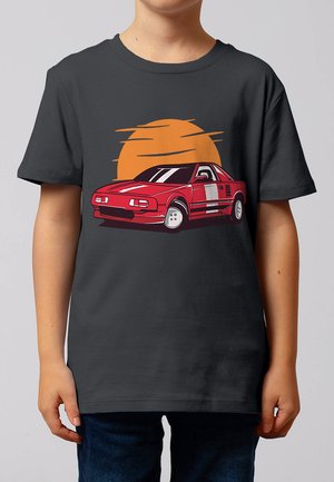 Enfant portant un t-shirt gris foncé avec une illustration d'une voiture de sport rouge et un soleil stylisé orange derrière la voiture.