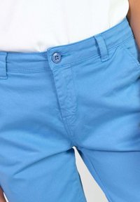 Lichtblauwe katoenen broek met een vlakke voorkant, enkele knoopsluiting en riemlussen, met een soepele textuur en nette naden.