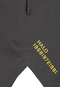 Ciemnoszara tkanina ze szczegółami szwów i żółtym napisem „HALO”, a następnie ciągiem cyfr wydrukowanym po przekątnej.