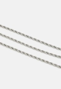 Catene metalliche argentate con un design intrecciato, composte da tre filamenti. Texture liscia con una finitura lucida, che riflette la luce.