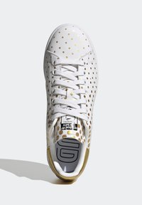 Vita sneakers med guldprickar, strukturerat läderöverdel, vita snören, guldaccenter på hälen och en tryckt logotyp på tungan.