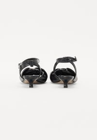 Escarpins noirs avec un dessus en cuir lisse, de fines brides de cheville et un petit talon effilé, dotés d'un bout rond et d'un intérieur doux.