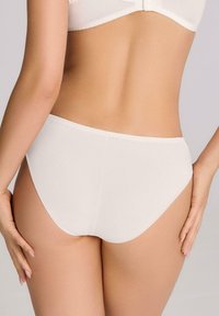 Białe bawełniane majtki w stylu slip, o gładkiej fakturze, z wysokim wycięciem nogawek i dopasowanym kroju. Bezszwowe plecy z minimalistycznym wzorem.