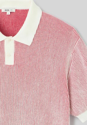 Polo à rayures verticales rouges et blanches, avec un col blanc et deux boutons sur la patte de boutonnage, étiqueté taille large.