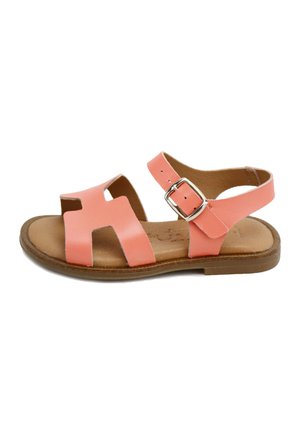 Sandalia de niña color coral con punta abierta, hebilla lateral, tiras de cuero, plantilla acolchada de color marrón claro y suela plana marrón.