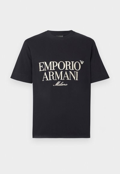 Čierne bavlnené tričko s veľkým, kontrastným krémovým nápisom "EMPORIO ARMANI Milano" na prednej strane a malým logom na hrudi.