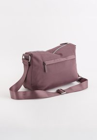 Lilla nylon crossbody taske med lynlås i toppen, frontlomme og justerbar rem. Glat tekstur med sølvfarvede hardware detaljer.