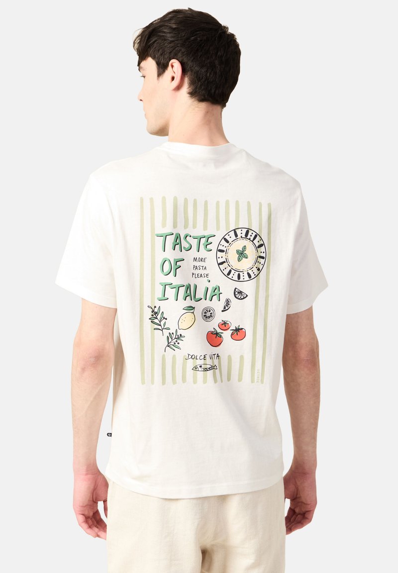 Valkoinen puuvillapaita, jossa on värikäs grafiikka selkäpuolella. Suunnittelussa on lauseita, vihanneksia ja kello, jotka on kehystetty pystysuorilla raidoilla.