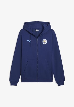 Granatowa bluza z kapturem i zamkiem błyskawicznym, przednimi kieszeniami, logo Puma na prawej piersi oraz herbem klubu piłkarskiego Manchester City na lewej piersi.