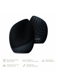 Dispositif de nettoyage facial noir avec une forme ergonomique, des surfaces texturées et des boutons de contrôle. Il dispose d'une technologie de pulsation douce pour le soin de la peau.