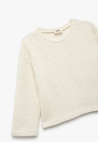 Sweter dzianinowy w kolorze off-white, z teksturowanym wzorem o różnych splotach. Krótki fason z okrągłym dekoltem i długimi rękawami.
