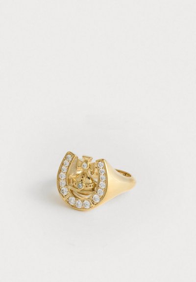 Gouden ring met een kroonontwerp binnen een hoefijzer, versierd met kleine heldere edelstenen, op een witte achtergrond.