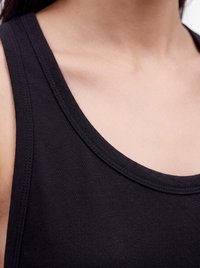 Close-up of a person wearing a black sleeveless top, focusing on the neckline and shoulder area.