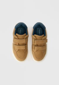 Pruunid sünteetilised jooksujalatsid, millel on kaks reguleeritavat Velcro rihma, tumesinine sisetald, kummist tallad ja minimalistlik disain.