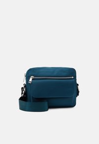 Borsa a tracolla turchese realizzata in tessuto liscio e resistente. Caratterizzata da una chiusura con zip, tasca frontale e una larga tracolla regolabile.
