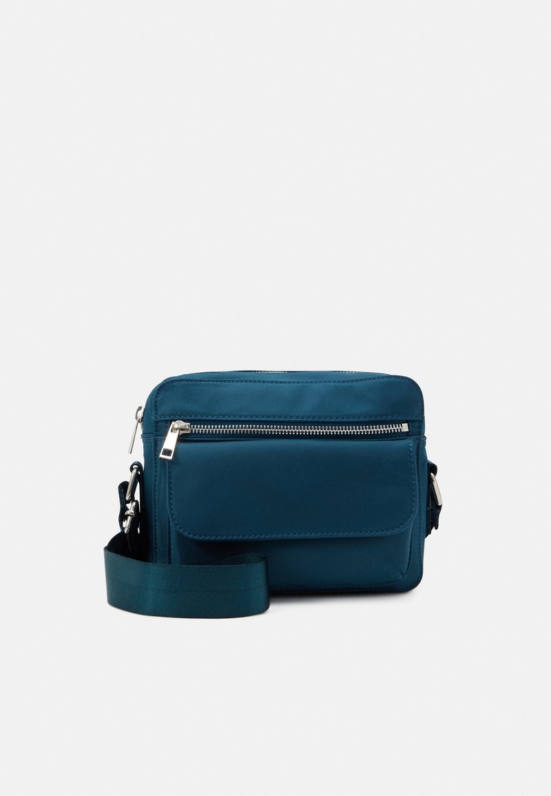 Teal crossbody bag made of smooth, durable fabric. Features a zip closure, front pocket, and a wide adjustable strap.