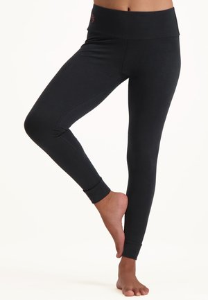 Schwarze Leggings aus dehnbarem Stoff, mit einem breiten Bund und enganliegender Passform mit Bündchen an den Knöcheln. Glatte Textur, minimalistische Details.