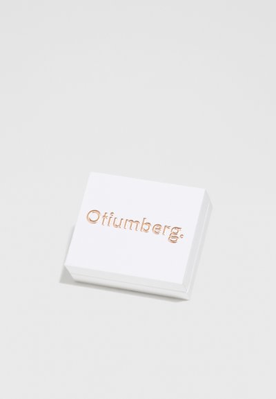 Balta stačiakampė dėžutė su suapvalintais kampais, turinti rožinio aukso iškilų logotipą "Otiumberg." Lygus matinio paviršiaus tekstūros dizainas yra minimalistiškas.