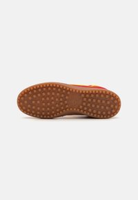 Nike-Schuhsohle mit einer strukturierten braunen Gummisohle, die ein Rippmuster für Traktion und Langlebigkeit aufweist.