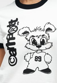 Λευκό μπλουζάκι με μαύρες λεπτομέρειες που απεικονίζει ένα καρτούν λαγό με υπερβολικά χαρακτηριστικά, φορώντας φανέλα με τον αριθμό '89'. Ο σχεδιασμός είναι τολμηρός και γραφικός.