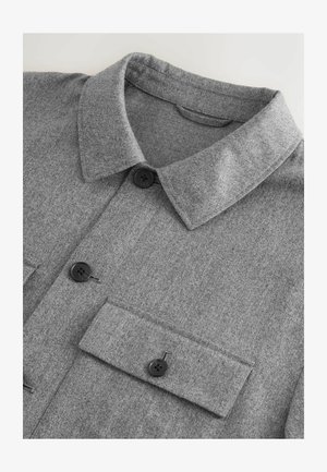 Grå uldblandet skjortejakke med spredt krave, to brystlommer og sorte knapper. Teksturen er blød og let meleret.