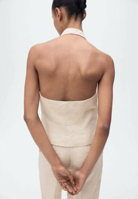 Light beige halter top, linen material, fitted design, open back, paired with matching fitted trousers, minimalistic style, no visible patterns.