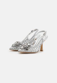 Décolleté argento con texture intrecciata e decorazioni floreali. Le punte sono affusolate e un tacco a blocco di altezza media completa il design.