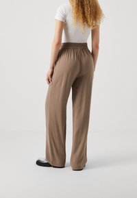 Brown wide-leg pants with an elastic waistband, made from a lightweight fabric, featuring a smooth texture and relaxed fit.