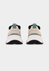 Ζευγάρι μπεζ, λευκών και πράσινων παπουτσιών Calvin Klein, εμφανισμένα από πίσω σε απλό ανοιχτό γκρι φόντο.