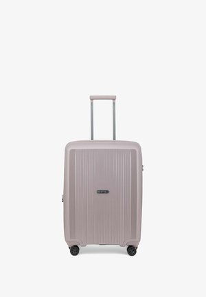 Valigia rigida di colore rosa chiaro, dotata di scanalature verticali, maniglia retrattile e quattro ruote nere per la mobilità.