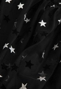 Czarna tkanina tiulowa z wzorem srebrnych i czarnych gwiazd. Tekstura jest miękka i przezroczysta, z fantazyjnym, dekoracyjnym elementem.