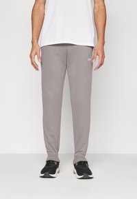 Grijze sweatpants van zachte stof, met een aangesloten pasvorm en een klein wit Puma-logo op de linker dij. Afgewerkt met ribgebreide manchetten.