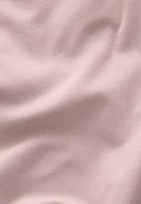 Tissu côtelé rose pâle avec des plis souples et irréguliers et de légères ombres, montrant une texture textile en gros plan. Aucune personne ni objet visible.