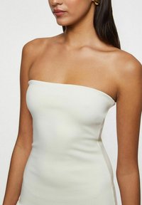 Strapless hvid bodycon-kjole, fremstillet af glat, strækbart materiale. Det tætsiddende design fremhæver silhuetten. Minimalistisk stil med rene linjer.