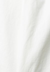 Tessuto bianco con una superficie morbida e leggermente strutturata; appare sgualcito, indicando un materiale leggero e traspirante adatto per i vestiti.
