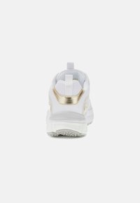 Hvide sneakers med en tekstureret overdel, metalliske guld accenter på hælen og en polstret sål, der har en løftestrop bagpå.