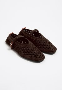 Scarpe in crochet marroni con punta appuntita, design aperto e una fascia sulla parte superiore del piede. Presentano una suola nera liscia e elementi decorativi in metallo.