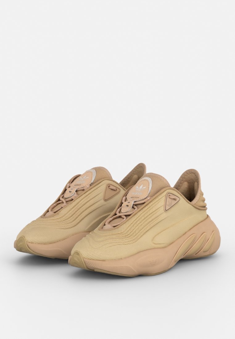 Sneaker beige con tomaia in mesh testurizzato, design snello e suola arrotondata. Presenta un logo discreto sulla linguetta e dettagli sagomati.