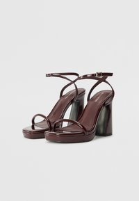 Glossy burgundy high-heeled sandals with a chunky block heel, slender crossover ankle straps, and a smooth platform sole.