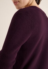 Lila Strickpullover mit strukturiertem Muster, der einen runden Ausschnitt und lange Ärmel hat. Der Stoff wirkt weich und gemütlich.