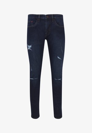 Tumed sinised denimpüksid kitsaste lõigetega, millel on reitega ja põlvede kohal rebendid, viis taskut ja nööbiga sulgus.