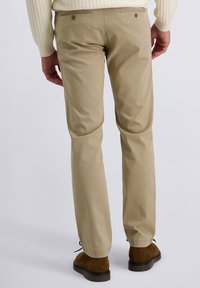 Pantalons beige, coupe droite, en coton avec une texture lisse. Comprend deux poches arrière avec boutons et une taille bien ajustée.