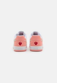 Pink and white sneakers with a soft texture. Features a heart logo in red on the heel and a contrasting red accent near the collar.