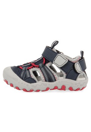 Sandalia ajustable en azul marino y gris con parte superior de malla, suela de goma, acentos rojos y diseño de punta cerrada con secciones cortadas para transpirabilidad.