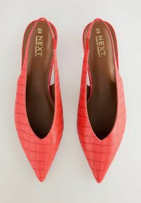 Scarpe slingback rosse con punta appuntita, caratterizzate da una texture a coccodrillo e una fodera interna marrone. Logo del marchio visibile sulla soletta.