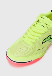Limegrön syntetläder sneaker med svarta detaljer, rosa sula, rund tå, perforeringar för ventilation och platta snören.