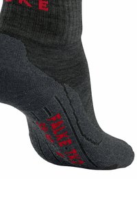 Graue Socken mit verstärkten Fersen- und Zehenbereichen. Rippendesign mit rotem "FALKE"-Logo und strukturierter Sohle für besseren Halt.