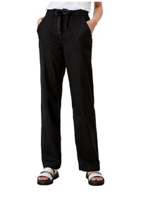 Un pantalon noir à jambe large avec une taille à cordon, des poches avant et une texture lisse. Assorti à des sandales à lanières blanches.